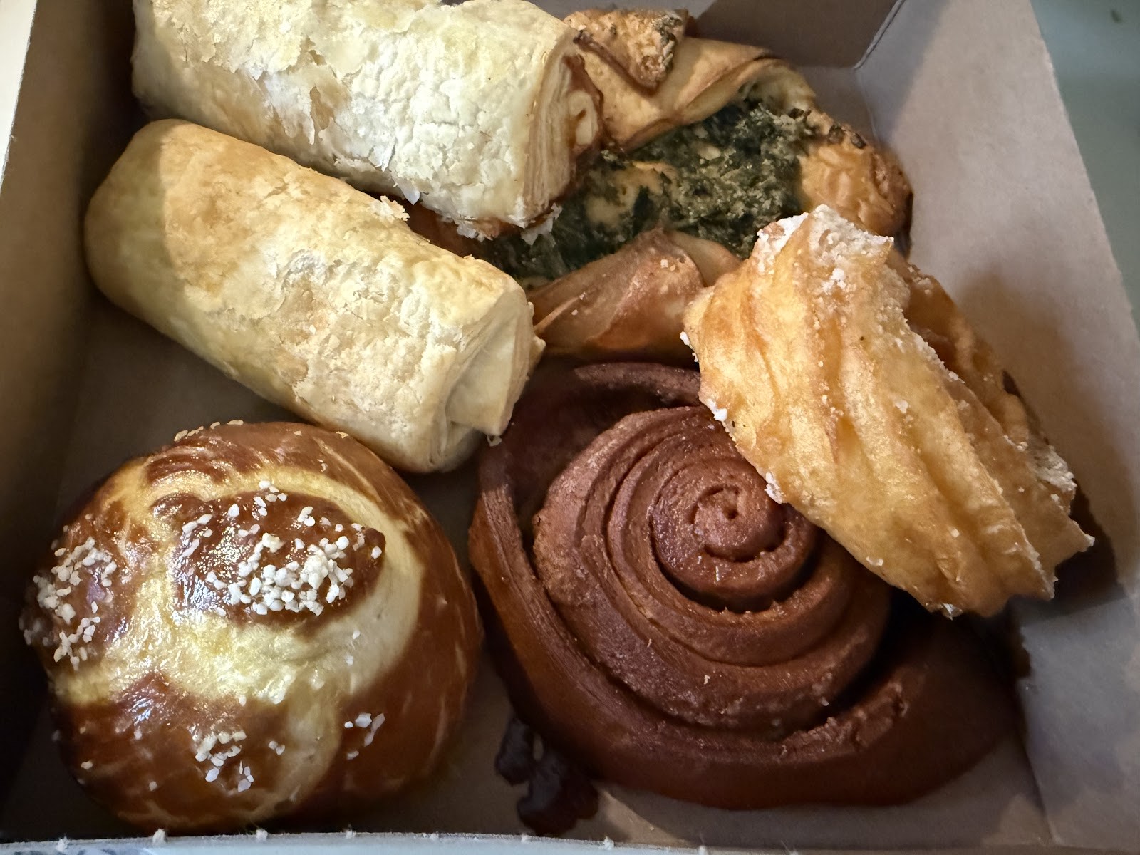A box of assorted German pastries including pretzel rolls and cinnamon swirls